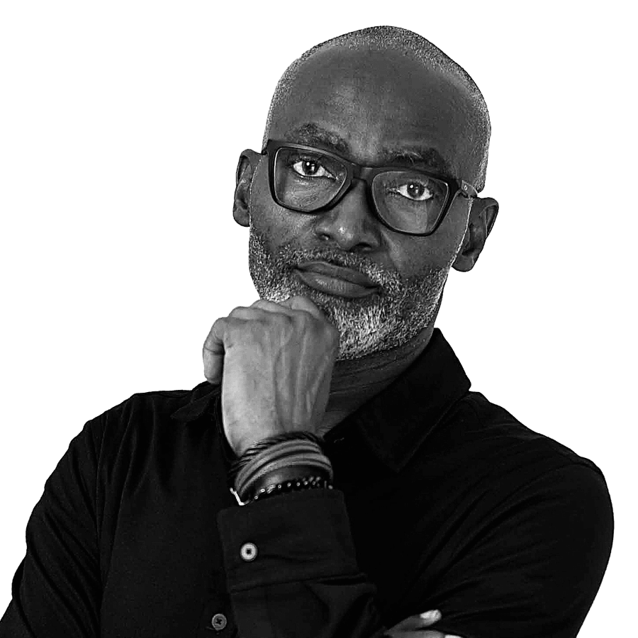 Utibe Ukim, hand to his chin, in a black shirt and dark-framed glasses.